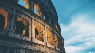 A view of the Colosseum of Rome during dusk, it's exterior lit up.