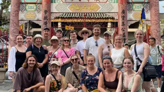 A Topdeck tour group poses for a group photo in front of an old assembly hall in Cambodia.