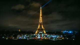 A view of the Eiffel Tower at night, it's lights shining like a beacon across the Paris skyline.