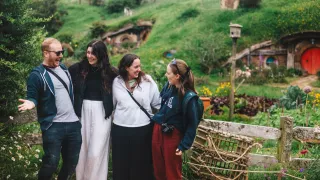 People stand together smiling at Hobbiton in the North Island of New Zealand.