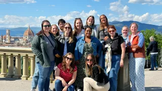 Small group of people posing together for a photo with a view of Florence behind them.