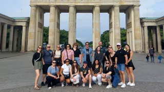Group of people standing in front of the Brandenburg Gate in Berlin.