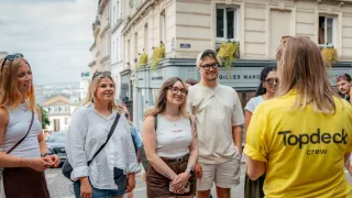 Small group of people smiling while listening to Trip Leader in yellow shirt speak.