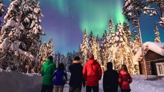 People standing in the snow at night with the northern lights in the sky.