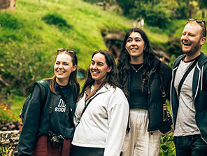 4 Topdeck travelers standing for a group photo at Hobbiton during their New Zealand Trip.