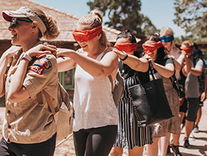 Topdeck Tour group being led in single file while blindfolded by a guide.