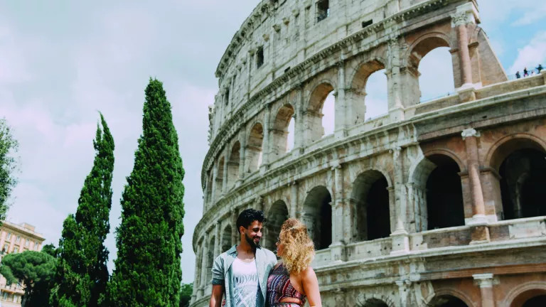 A romantic couple standing in front of the Colosseum