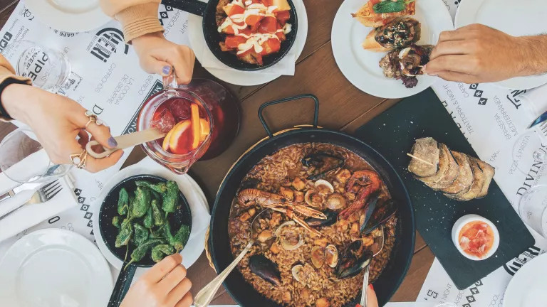 plates of food with people serving themselves food from different dishes