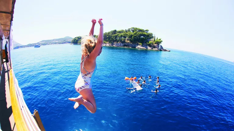 Woman jumping off a boat into the sea in Croatia