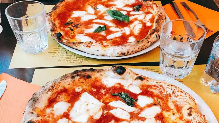 Two margarita pizzas on a table at a restaurant 