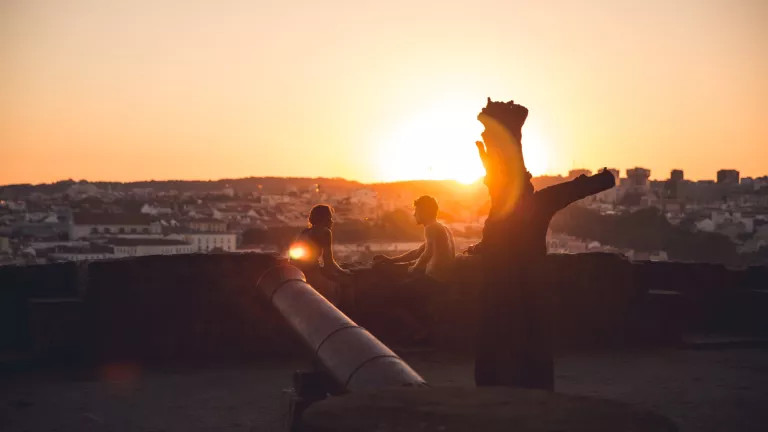 A couple sitting on a roof at sunset
