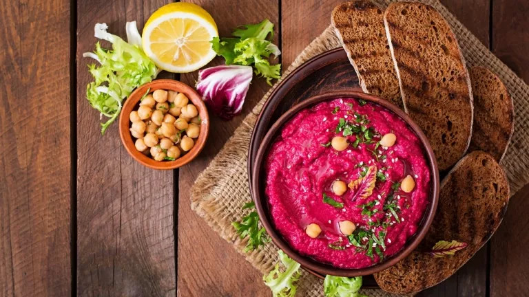 A table with pink hummus and chickpeas in a small bowl on the side