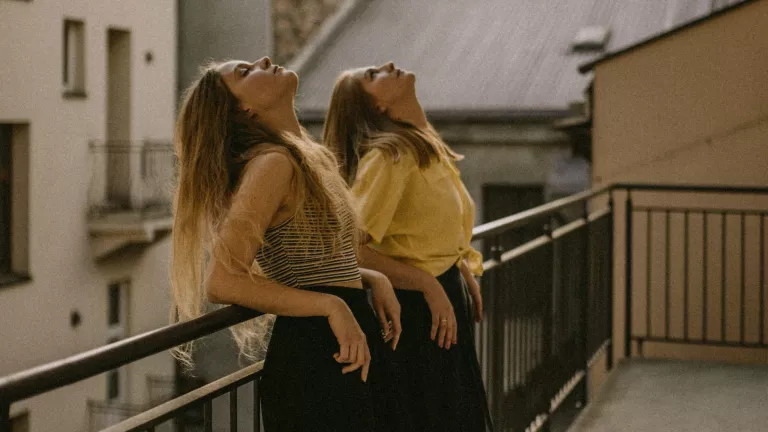 Two women leaning on a railing, with their heads up