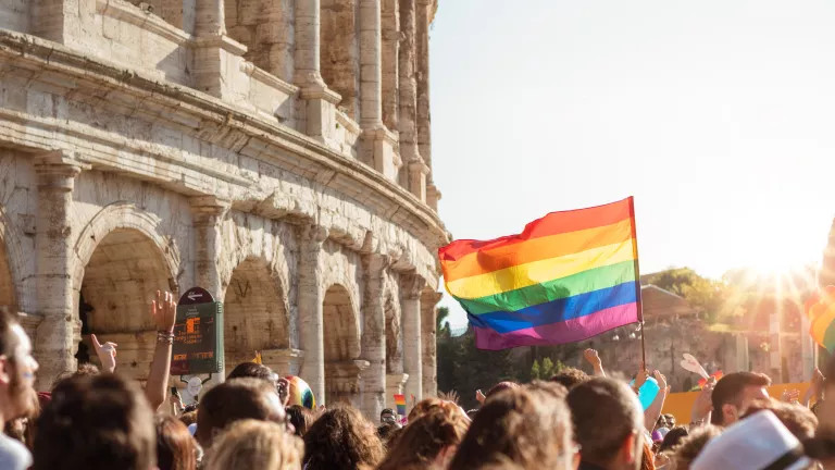 A pride march, in the background is the colosseum