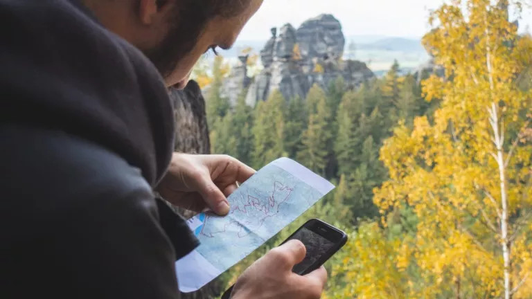 Man using a map and his phone to navigate a forest