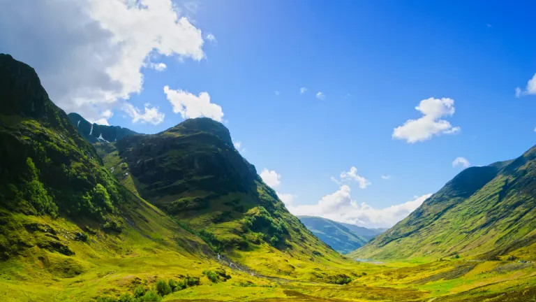 Green Scottish mountains and a bright blue sky
