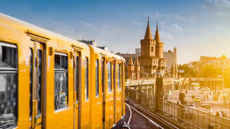 A yellow train drives over Berlin skyline