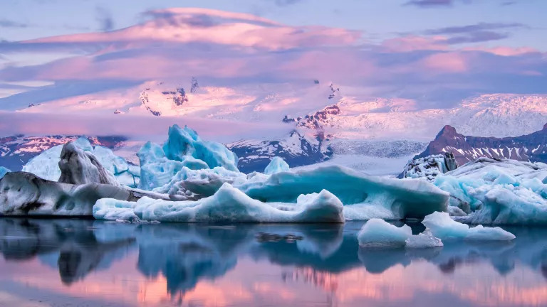 An orange and pink sunset over snow, ice and water in Iceland