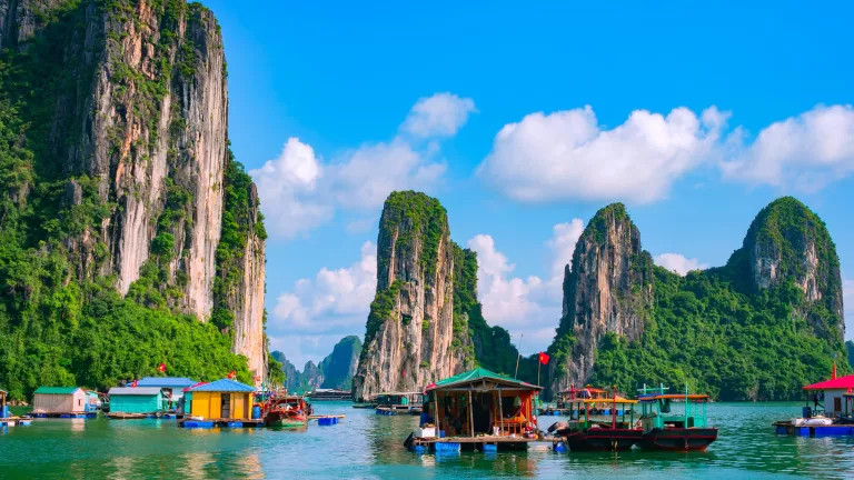 Mountains surrounding a body of water with floating houses on them in Vietnam