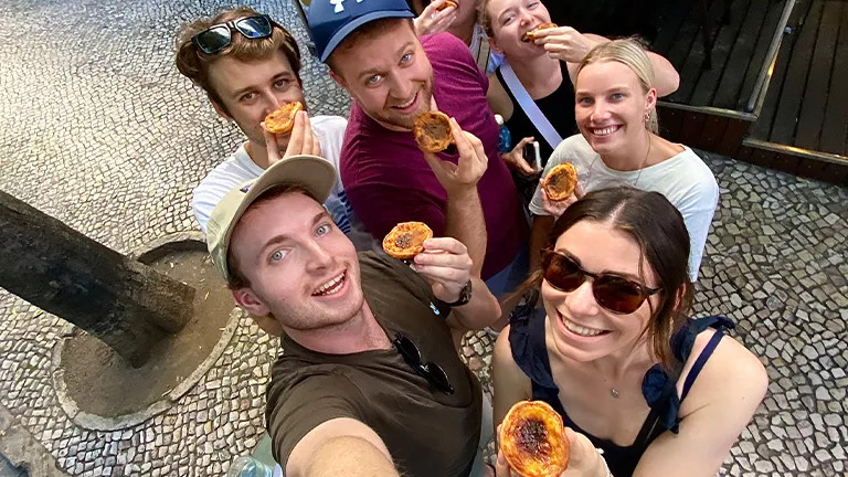 Group of people standing together holding pastel de natas.