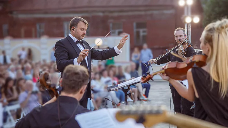  Conductor leads orchestra performance in public outdoor space in Vienna.