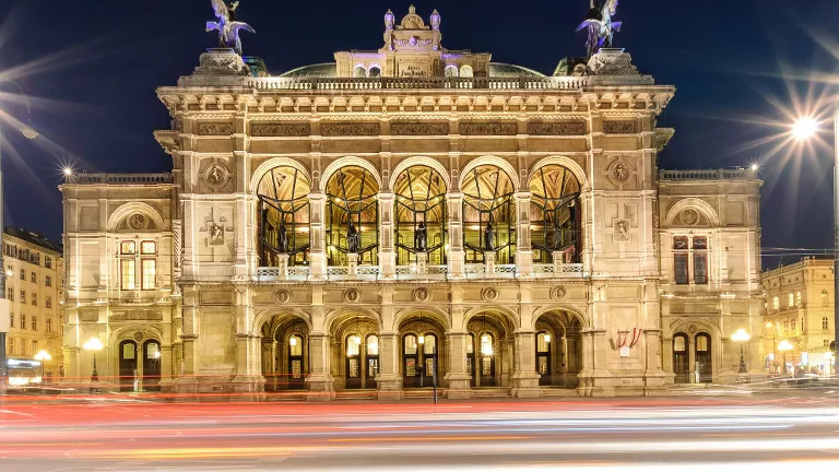 A traditional building known as the Vienna State Opera lit up at night.