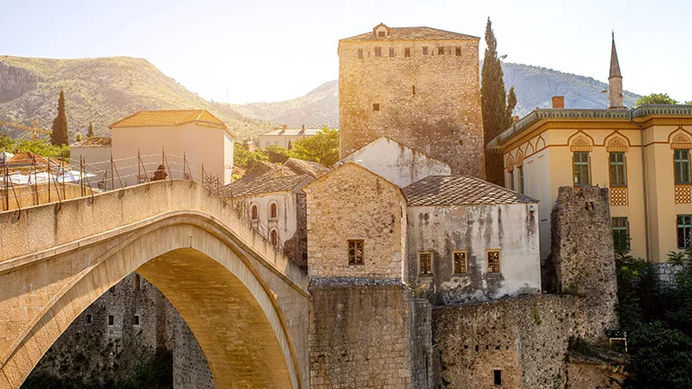 Mostar Bridge next to stone buildings.