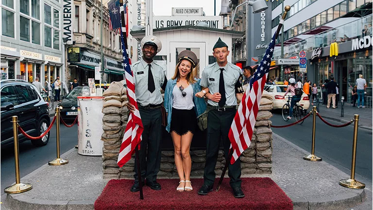 Woman posing with two American soldiers at Checkpoint Charlie in Berlin