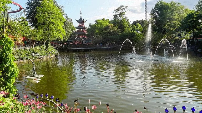  Man made pond with water feature surrounded by lush garden.