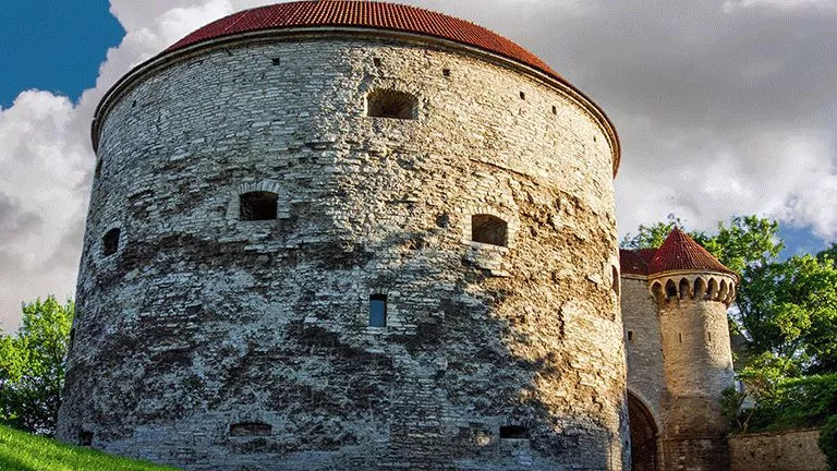 Large curved stone building with small windows and red roof.