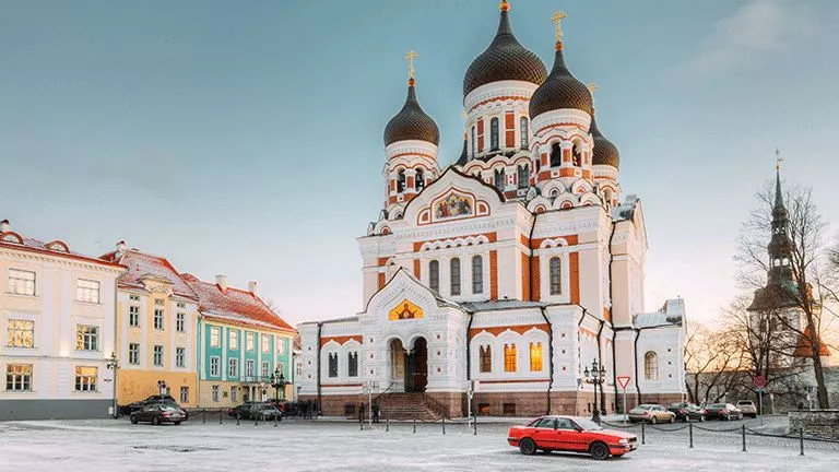 White cathedral with orange detailing and large domed towers.