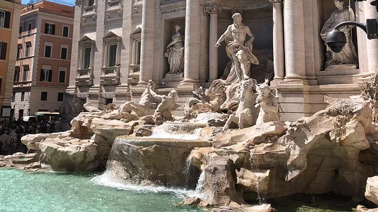 Statues standing above the water of the Trevi Fountain in Rome.