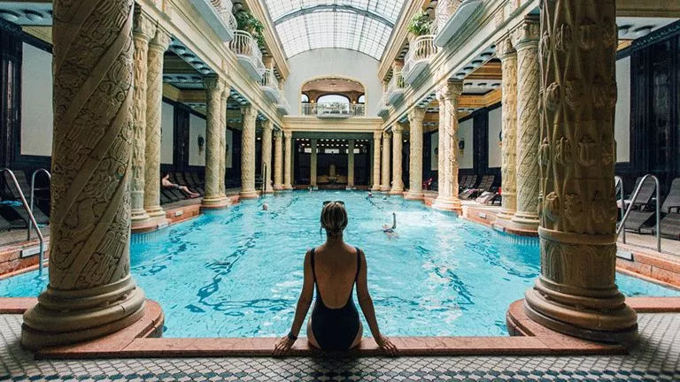 Person sitting on the edge of a swimming pool at the Budapest Thermal Baths.
