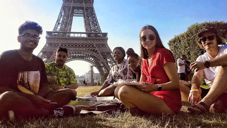 People sitting together on a blanket in front of the Eiffel Tower.
