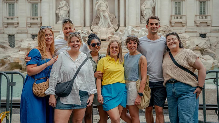 Small group of people standing in front of the Trevi Fountain in Rome.
