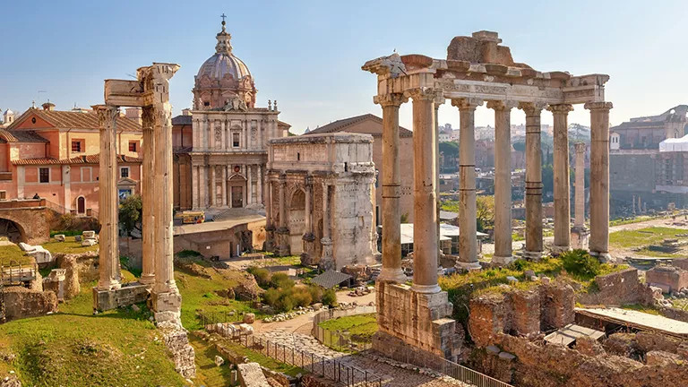 Ancient Roman ruins including large stone pillars set among the city of Rome.