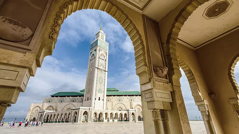 View of the Hassan II Mosque in Casablanca through the archway of a nearby building.