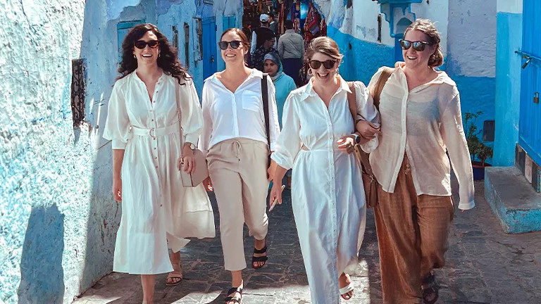People walking through street in Moroco with blue walls.