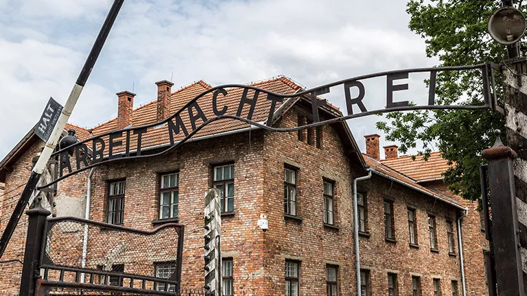 Brick building with iron sign at gated entrance.