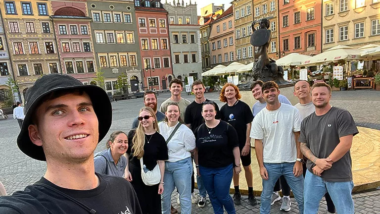 Group of people taking a selfie together in an open city square.