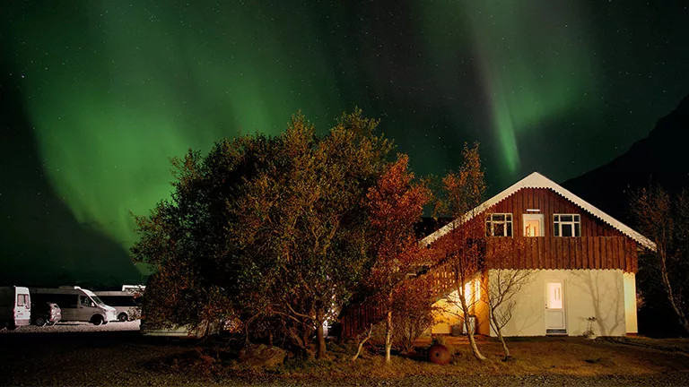 Aurora Borealis over a house and trees at night.