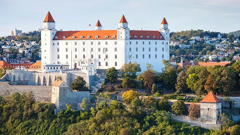 Large, white castle like building with a red roof and turrets on each corner.