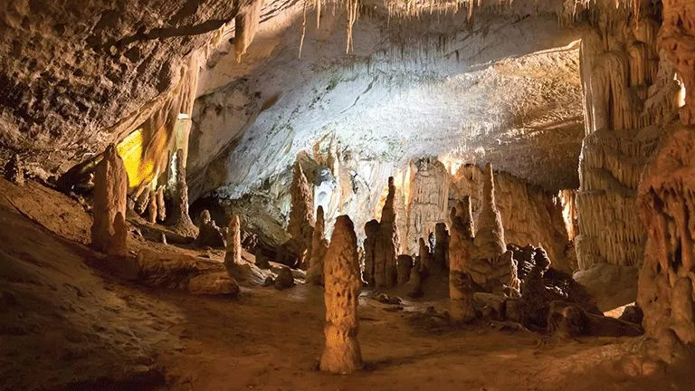 Postojna Cave in Slovenia lit up with large stalactites and stalagmites.