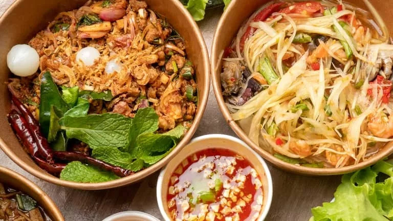 Two large bowls of Thai salad with a smaller bowl with a dipping sauce.