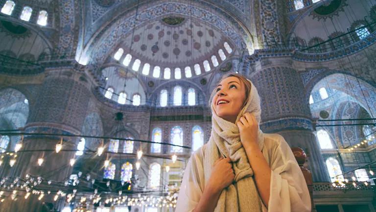 Person looks up at the detailed ceiling of the Blue Mosque in Istanbul.