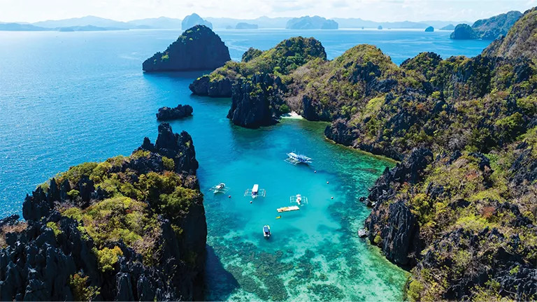 A small bay with boats and bright blue water in the Philippines.