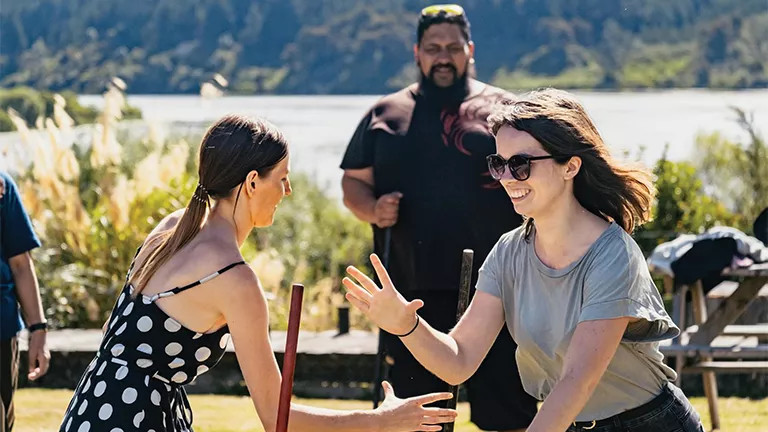 Two people making a hand motion at a cultural experience in New Zealand.