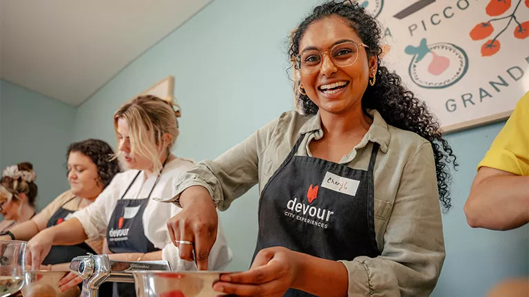 Person wears an apron and mixes something in a metal bowl in an Italian cooking class.