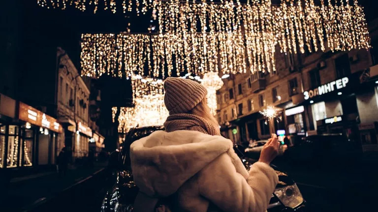 A woman holding a sparkler under fairy lights