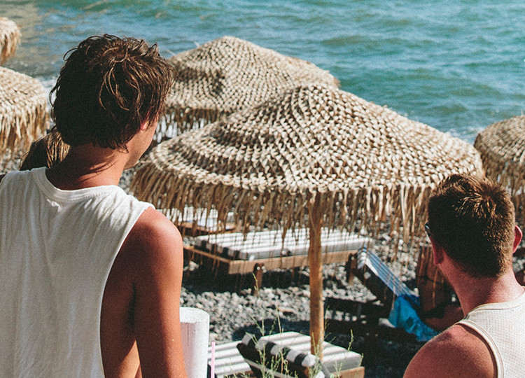 Topdeck travelers hanging around a beach in Mykonos on a sunny day.